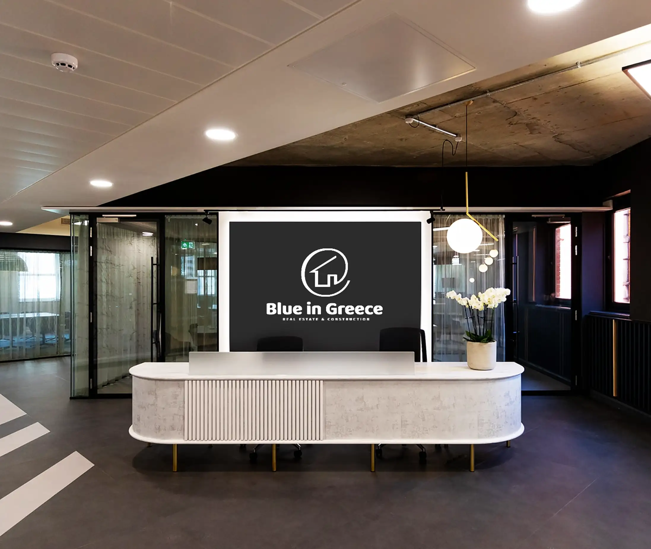 The Blue in Greece logo on a screen above a curved reception desk in a modern office